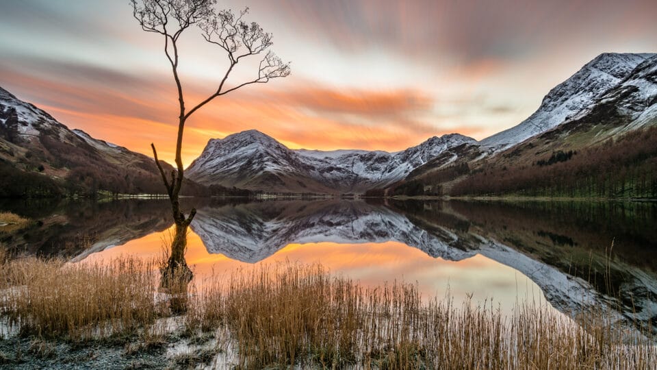 Dramatic Orange Sunrise Over Snow Covered Mountains In Buttermere in The Lake District, UK.
